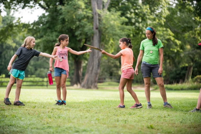 One girl handing a stick to another girl